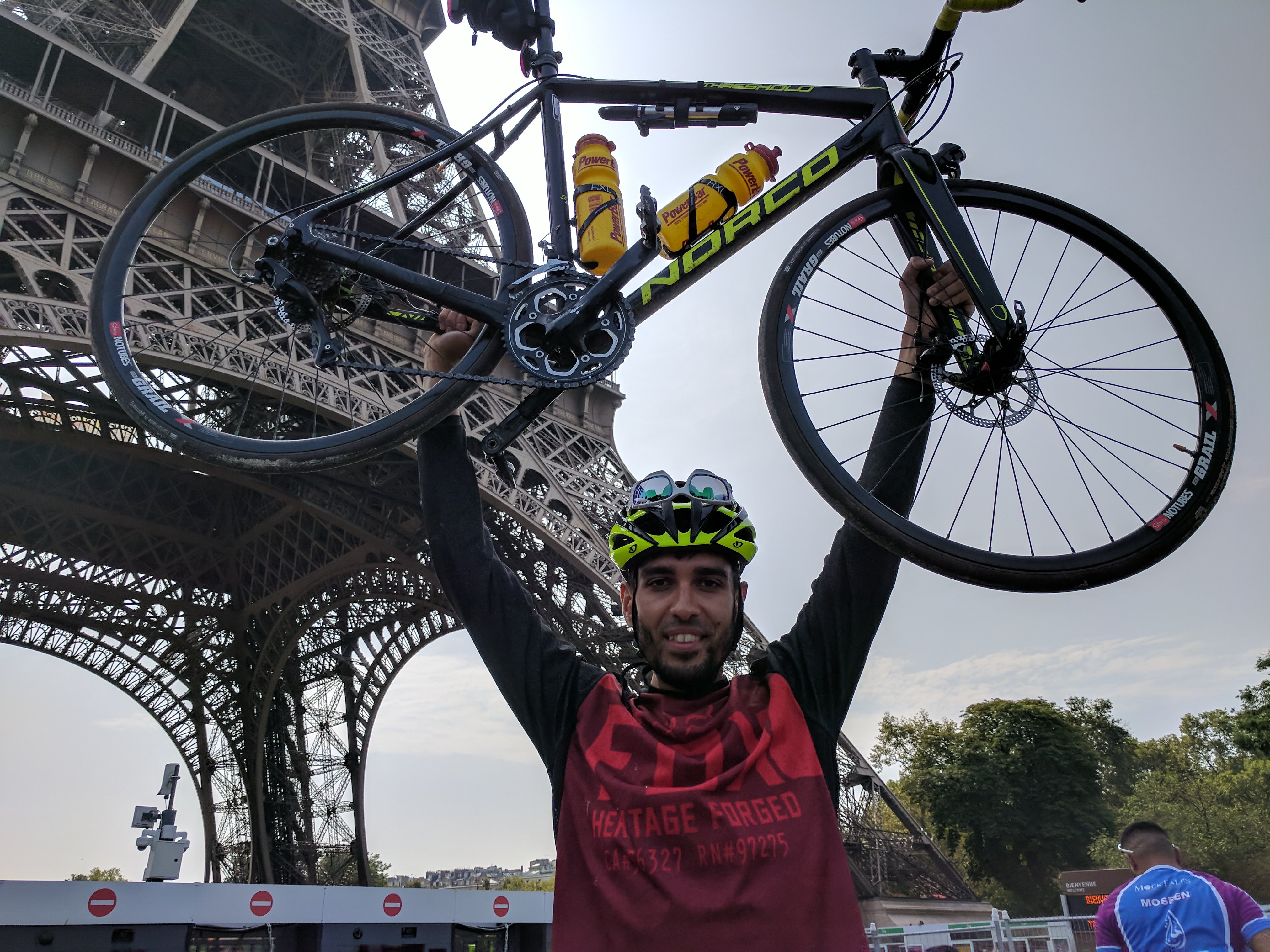 Bari Khan raises his bike aloft in front of the Eiffel Tower in Paris after completing his ride from London in 2017. Image:Bari Khan raises his bike aloft in front of the Eiffel Tower in Paris after completing his ride from London in 2017.