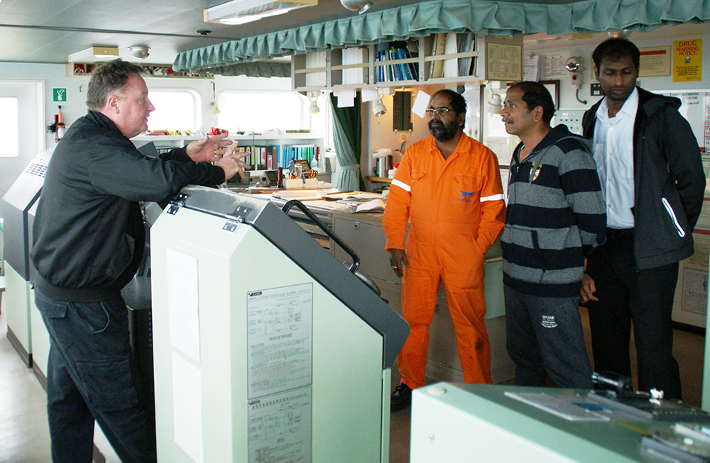 Title: deepsea pilot captain Paul Lanaghan discusses the passage with Cygnus Leaders master and navigational officers Title: deepsea pilot captain Paul Lanaghan discusses the passage with Cygnus Leaders master and navigational officers