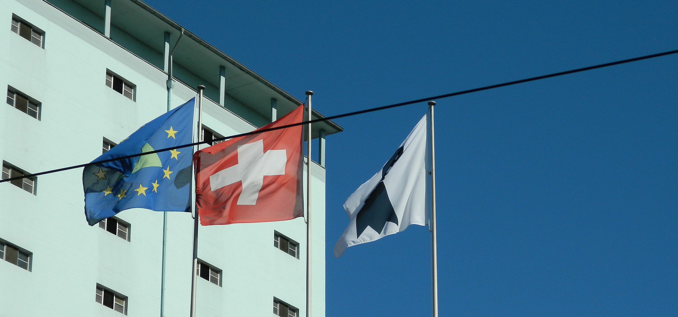 Die drei Flaggen symbolisieren grenzüberschreitende Zusammenarbeit in der Region Basel. Der Rheinknie umringt von europäische Sternen, das Schweizer Kreuz und der Baslerstab. Image:Die drei Flaggen symbolisieren grenzüberschreitende Zusammenarbeit in der Region Basel. Der Rheinknie umringt von europäische Sternen, das Schweizer Kreuz und der Baslerstab.