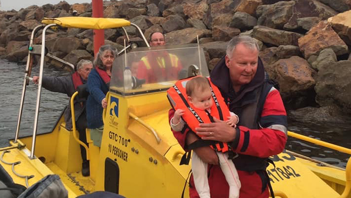 AIMPE member Sean Connolly drives the Far Saracen's FRC, as a Victoria Police officer holds a baby during the Mallacoota evacuation. Seafarers from various Merchant Navy crews assisted their Australian firefighting colleagues on the ground by helping with coastal evacuations during the height of the bushfire emergencies. Image: courtesy Far Saracen crew members Image:AIMPE member Sean Connolly drives the Far Saracen's FRC, as a Victoria Police officer holds a baby during the Mallacoota evacuation. Seafarers from various Merchant Navy crews assisted their Australian firefighting colleagues on the ground by helping with coastal evacuations during the height of the bushfire emergencies. Image: courtesy Far Saracen crew members
