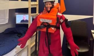 Penny Hogan of Unity Bank dons PPE during a safety drill challenge in the Nautilus ship's cabin stand. Image:Penny Hogan of Unity Bank dons PPE during a safety drill challenge in the Nautilus ship's cabin stand.